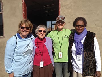 (From left) Gayla Congdon, founder of Amor Ministries and director of Women of Strength, stands in front of a completed home with Betty Eves of Oregon (at 85, the oldest participant at Women of Strength South Africa 2014); April Congdon, an Amor Ministries missionary, Yucatan, Mexico; and Pastor Noma of South Africa. Two years earlier, at Women of Strength 2012, participants helped build a home for Pastor Noma.